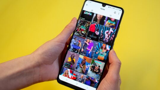 Жінка серфінг на Tiktok показує найпопулярніші відео Tiktok у сітці на додатку на своєму телефоні.