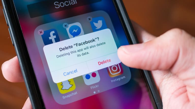 Людина, яка роздумує, чи видаляти додаток Facebook з телефону (зображення файлу).