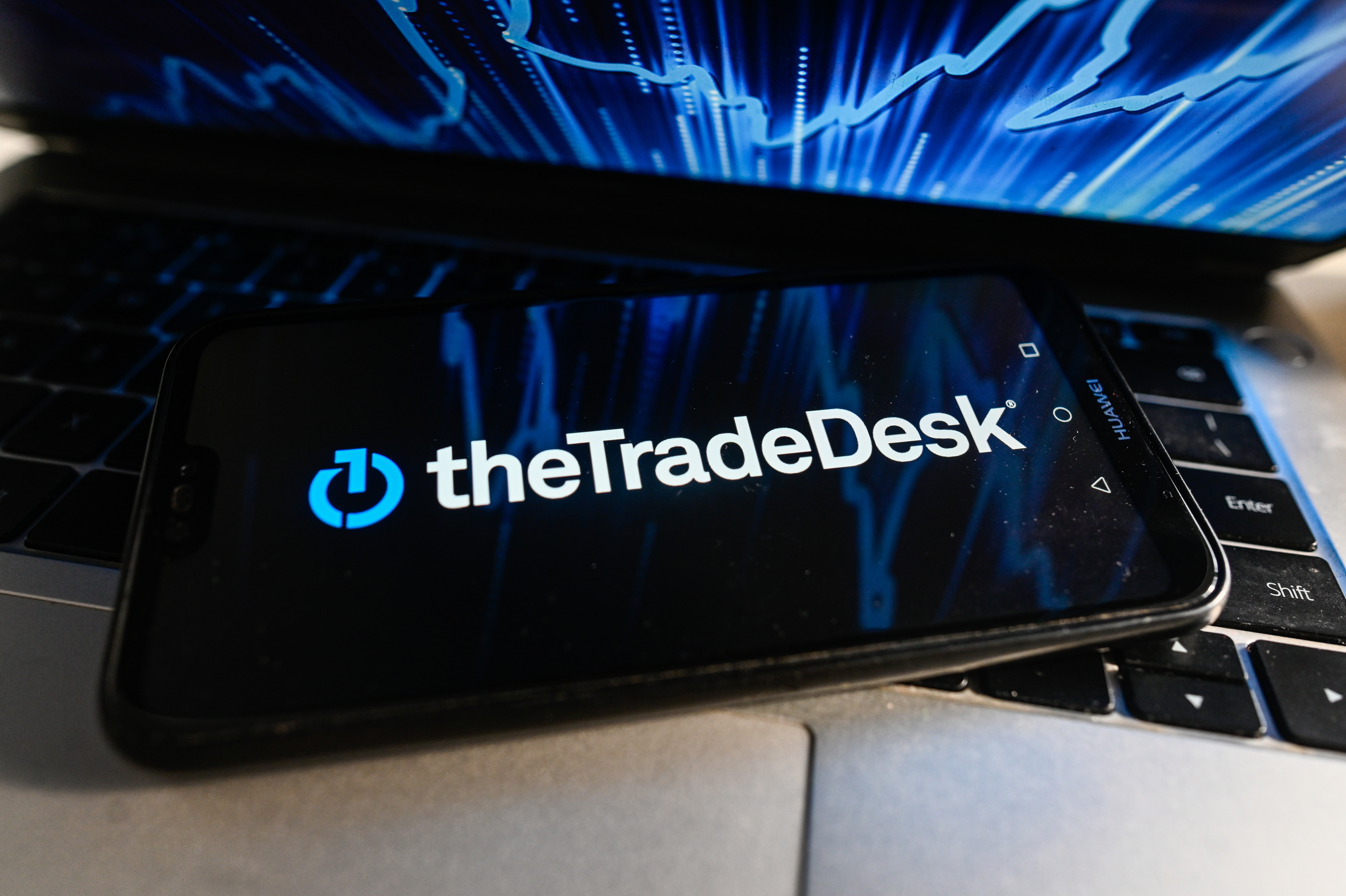Логотип компанії The Trade Desk на смартфоні, який знаходиться над ноутбуком