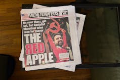 У газеті зображено людину, яка тримає червоний серп і киту, а в заголовку написано «червоне яблуко».